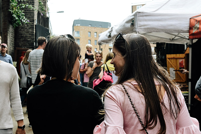 Photo of two women arm in arm at a market