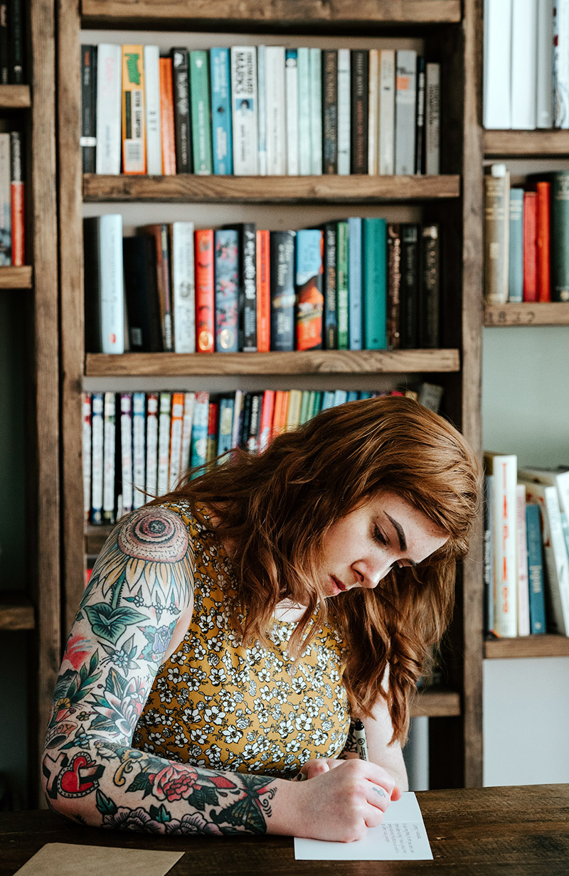 Woman writing in front of bookshelf