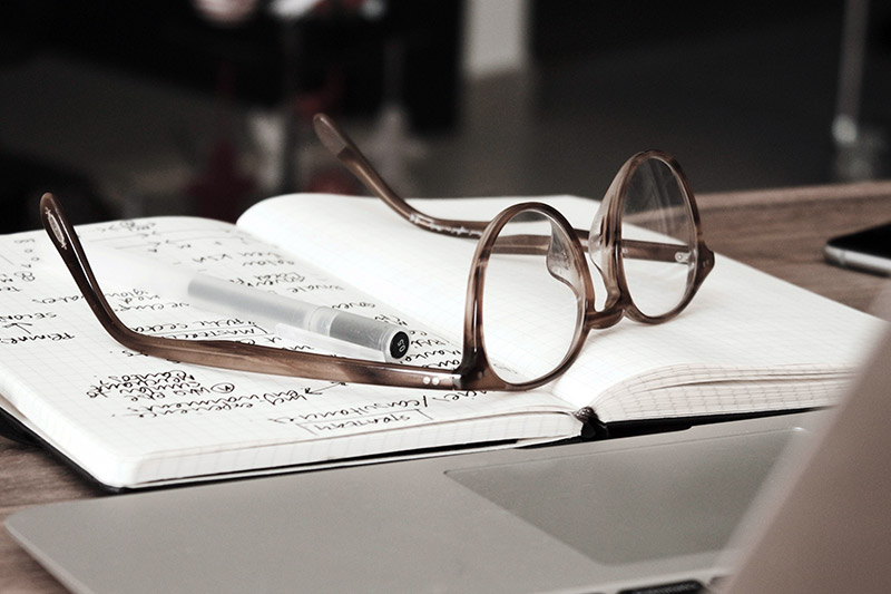 Photo of a pair of glasses and pen on a notepad